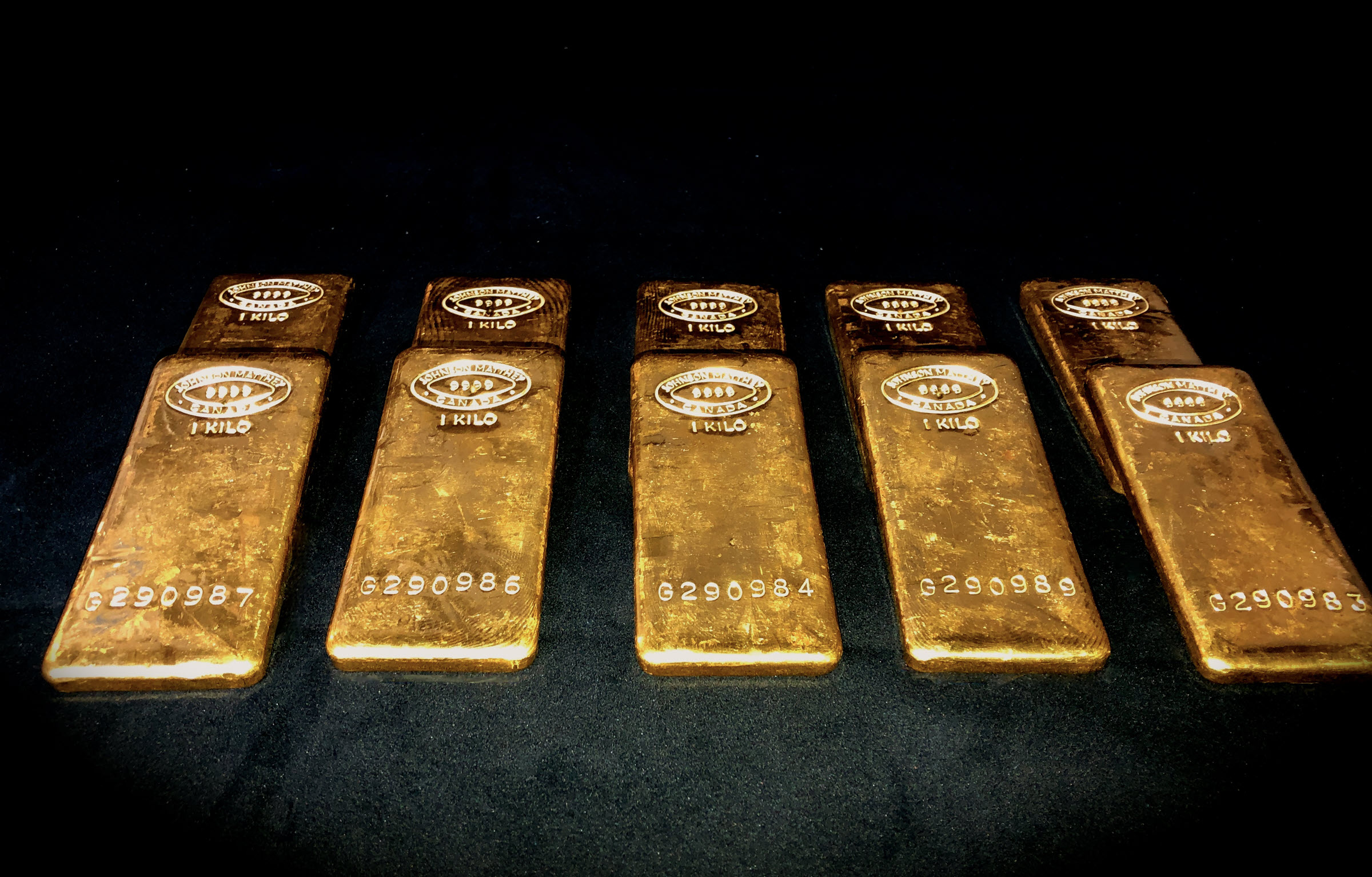 10 Gold Johnson Matthey bars on a black background within a vault